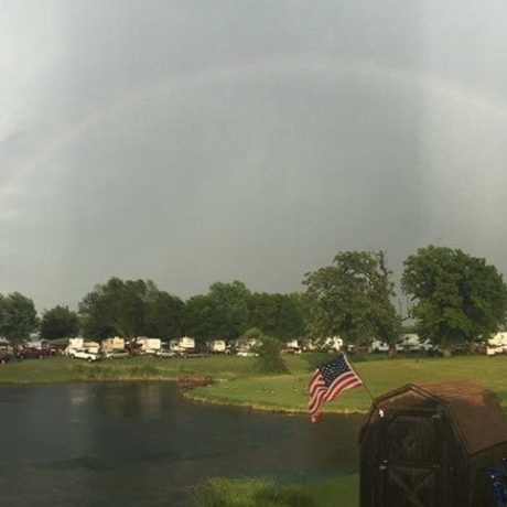 view of pond and RV sites with rainbow background at Shady Lakes RV Resort