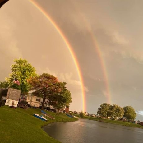 view of pond and RV sites with rainbow background at Shady Lakes RV Resort